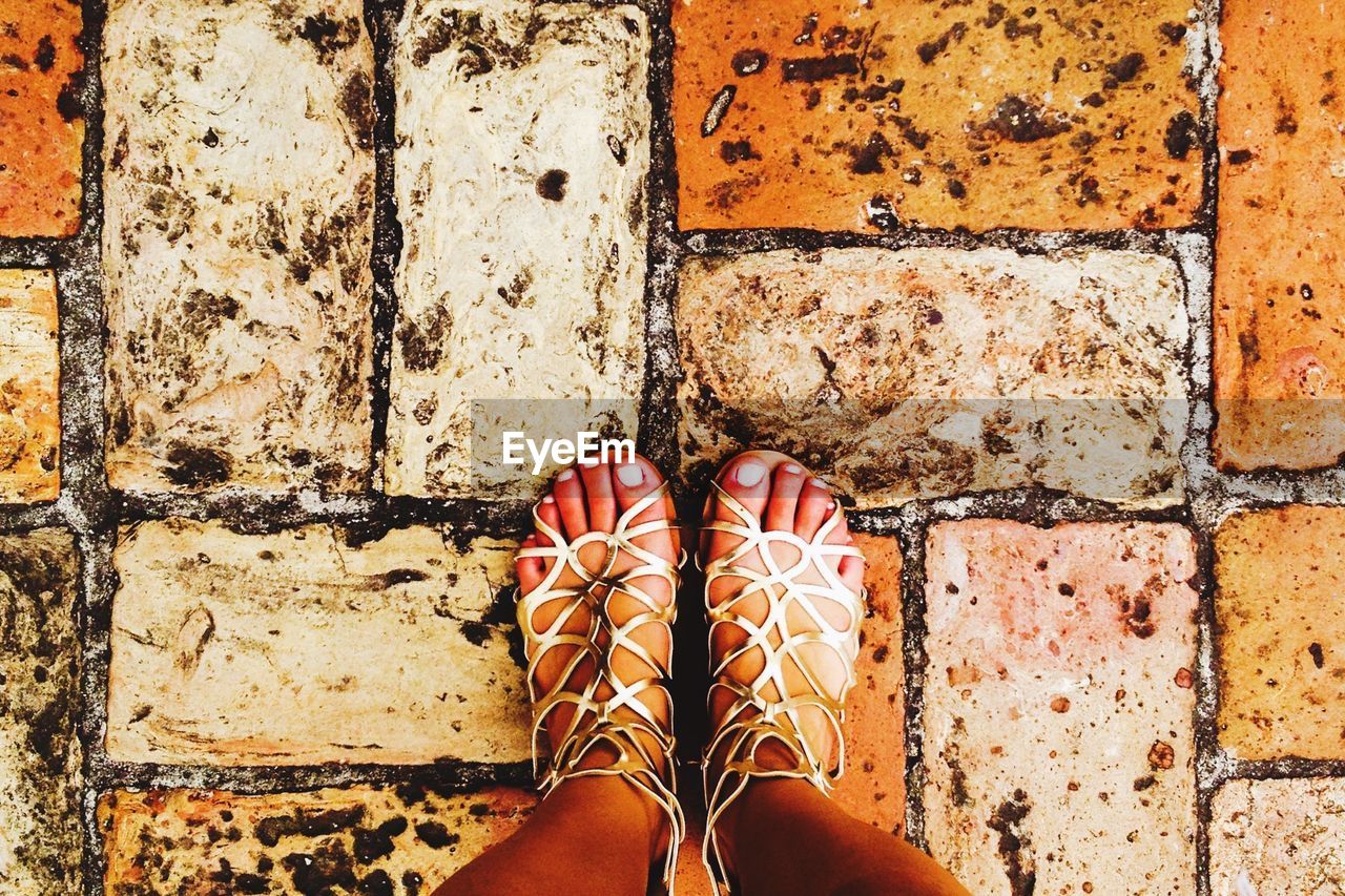 Feet of woman standing on old pavement