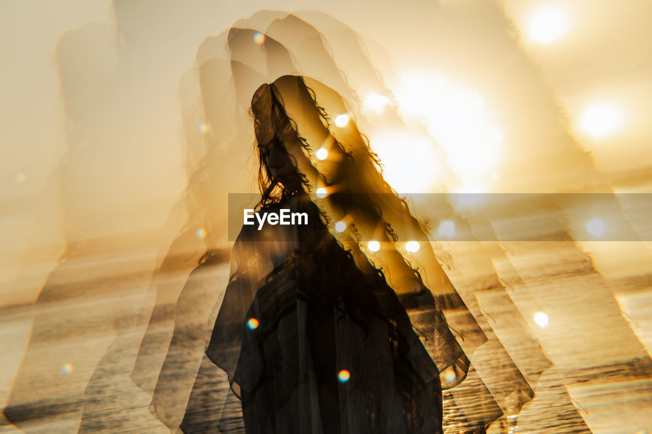 Rear view of woman walking on beach during sunset sun