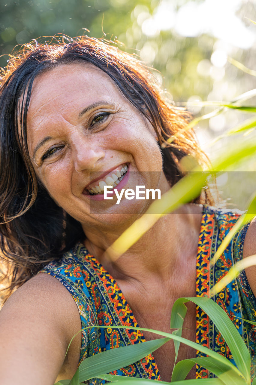 Portrait of beautiful middle aged woman in front of a fountain in a park at sunset