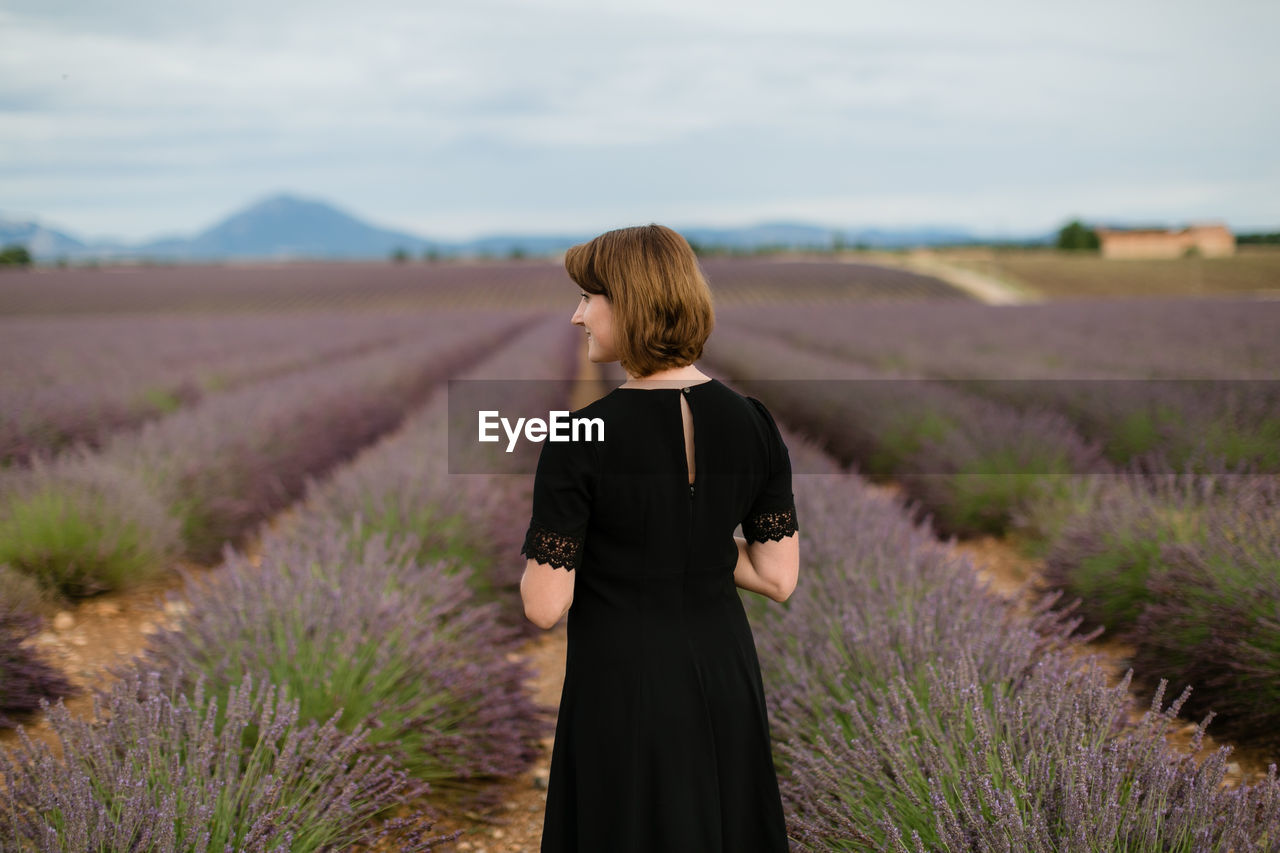 Rear view of woman standing between blossoms of lavender field 