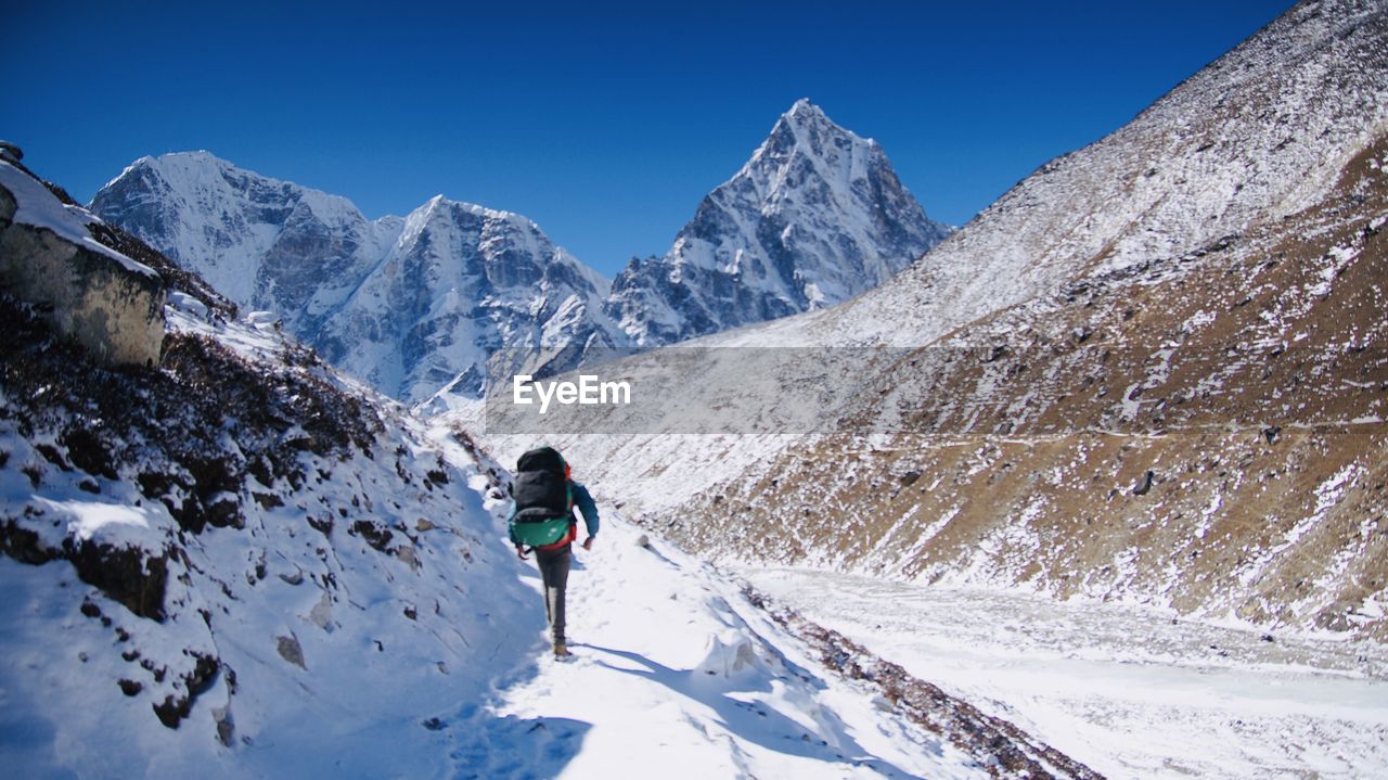 Man walking on snowcapped mountain against sky