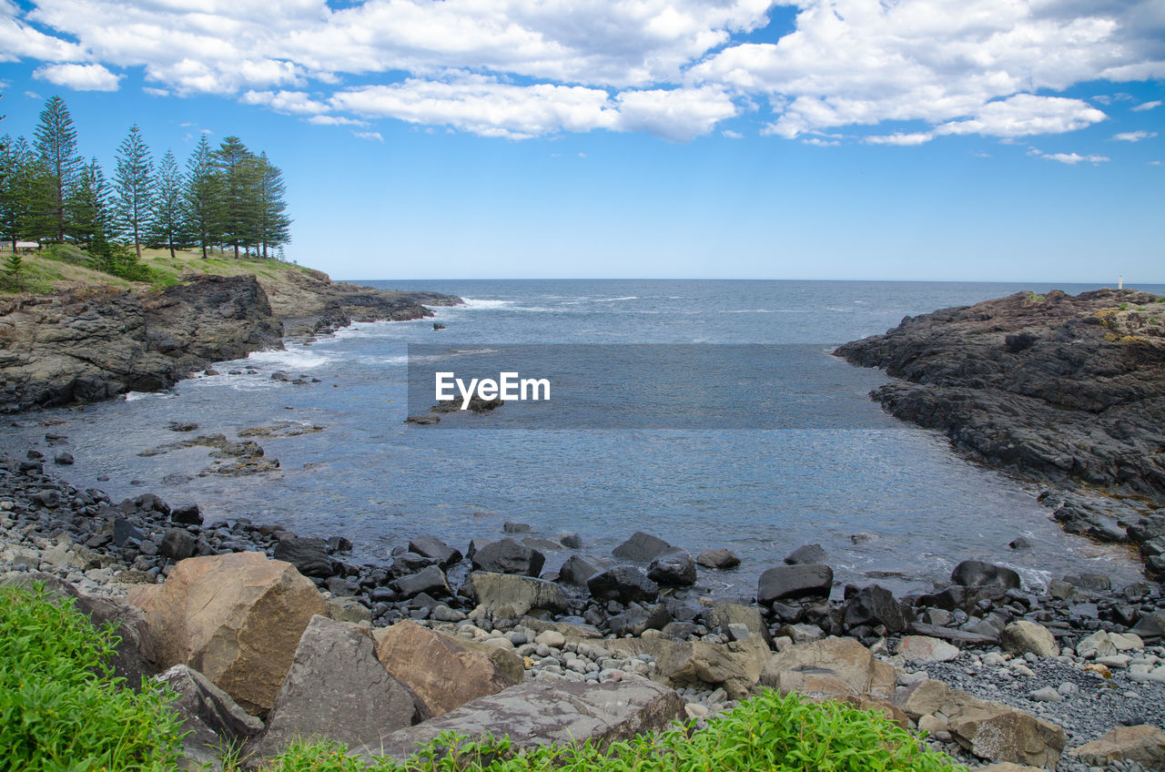 ROCKS BY SEA AGAINST SKY