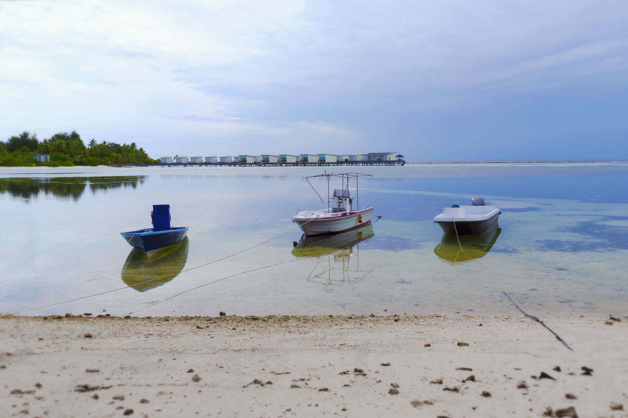 Boats moored on beach against sky