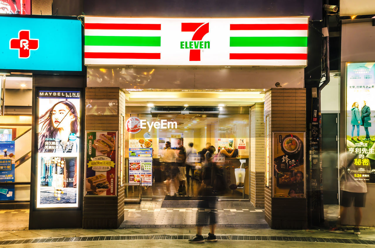 PEOPLE WALKING ON ILLUMINATED STORE