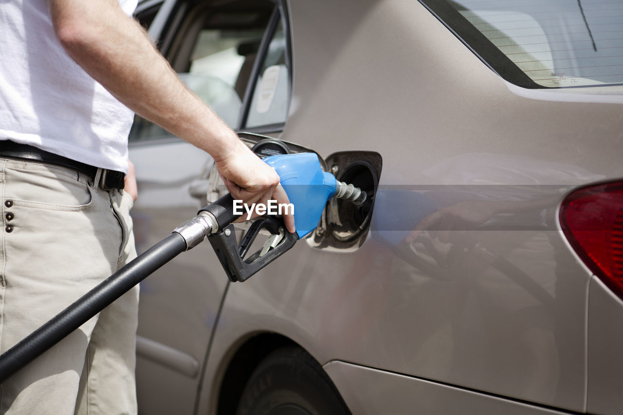 Midsection man refueling car at gas station