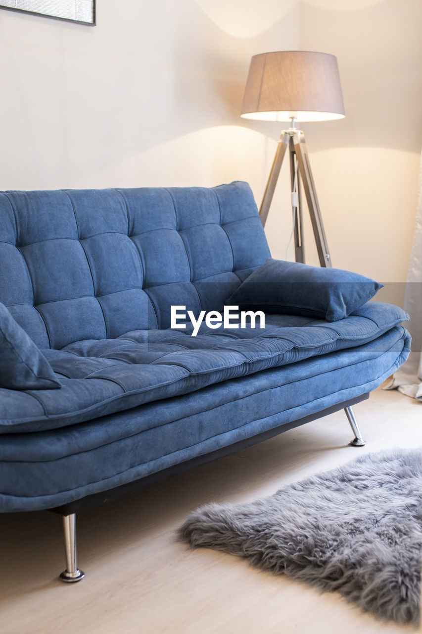 Modern interior close up, blue sofa and corner lamp in an airbnb.