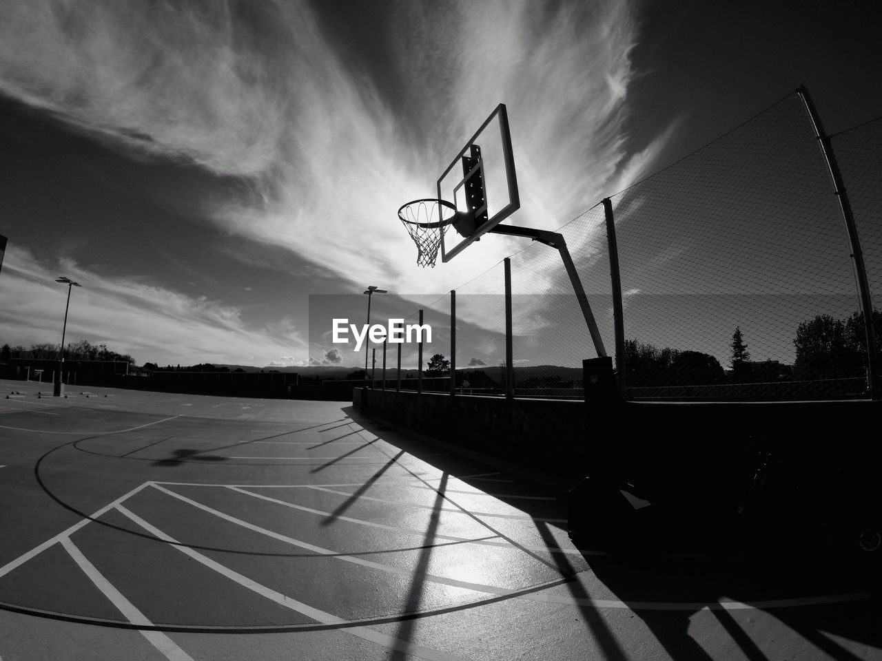 Low angle view of basketball hoop at court against cloudy sky