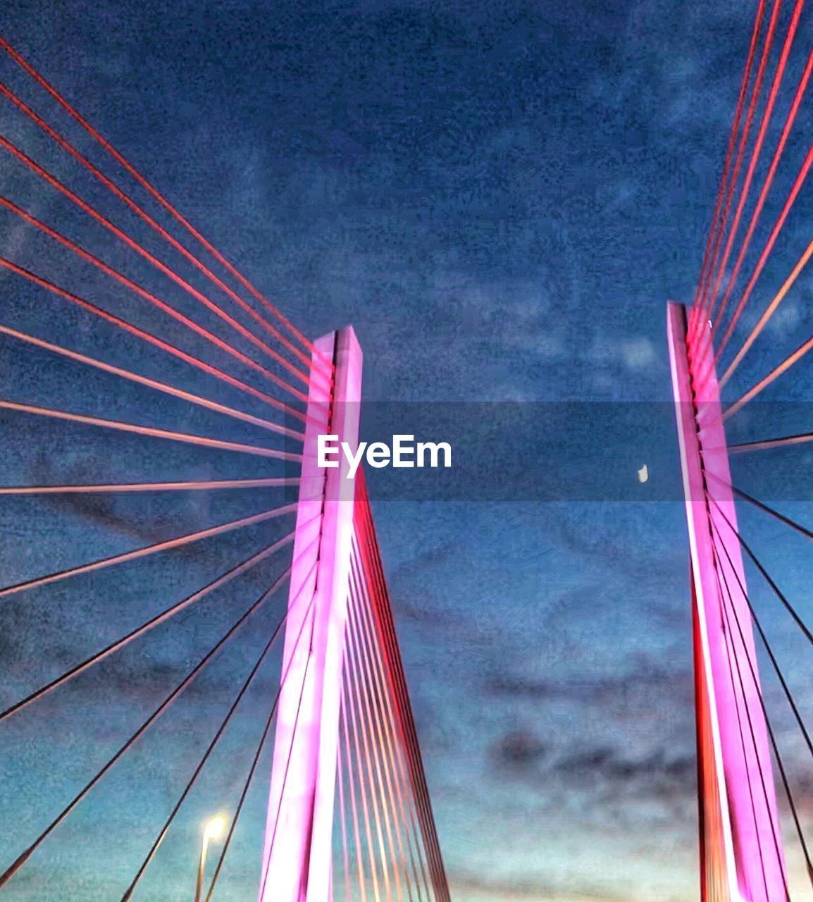 LOW ANGLE VIEW OF ILLUMINATED BRIDGE AGAINST BLUE SKY AT NIGHT