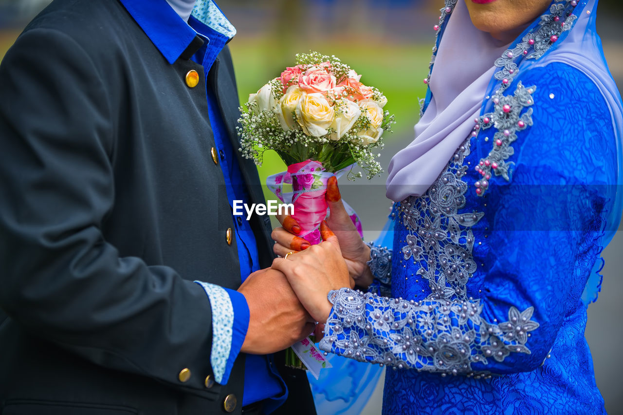 MIDSECTION OF WOMAN HOLDING BOUQUET OF FLOWER