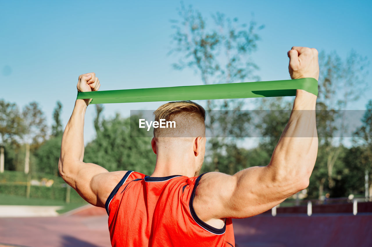 Midsection of man with arms raised against sky