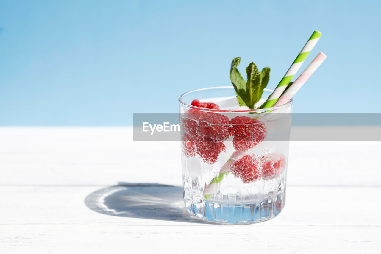 Chilled soda, water, cocktail with fresh berries and mint in a glass on a pastel background. summer 