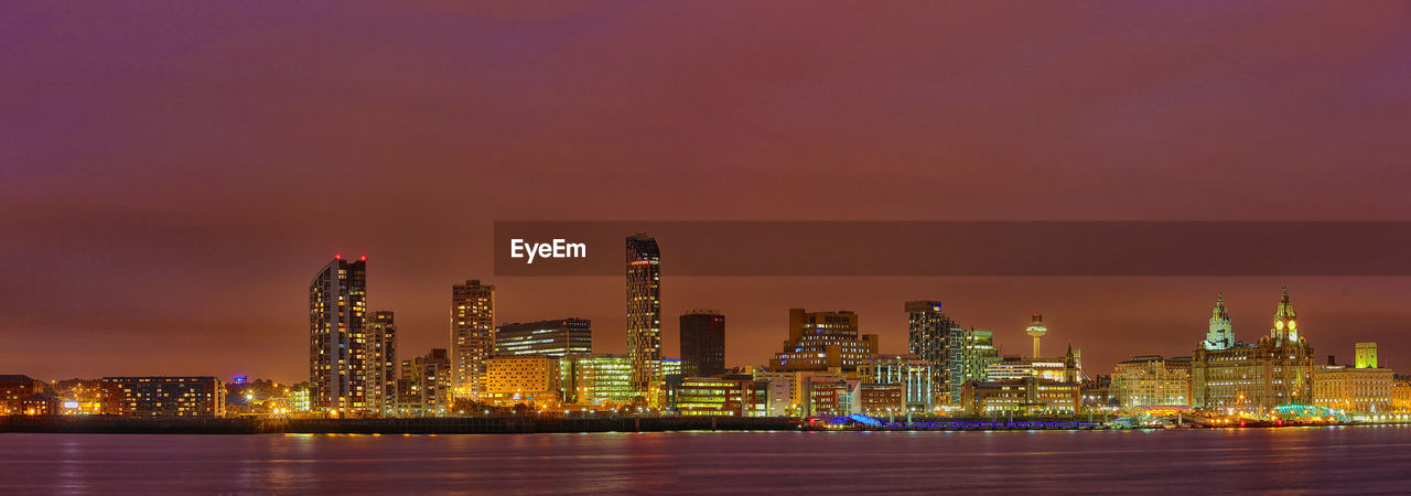 Distant view of west and alexandra towers in illuminated city by lake at night