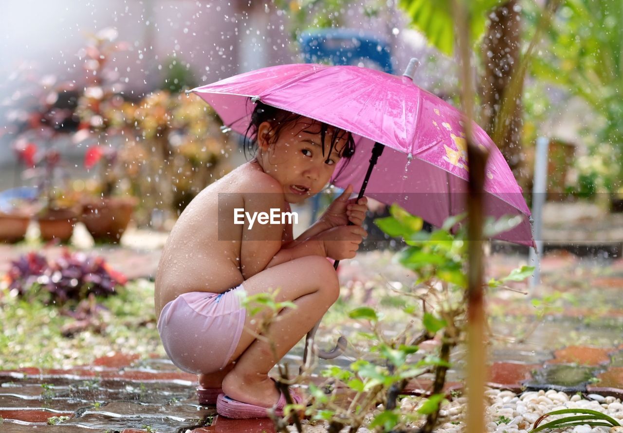 Portrait of cute girl with umbrella during rainy season