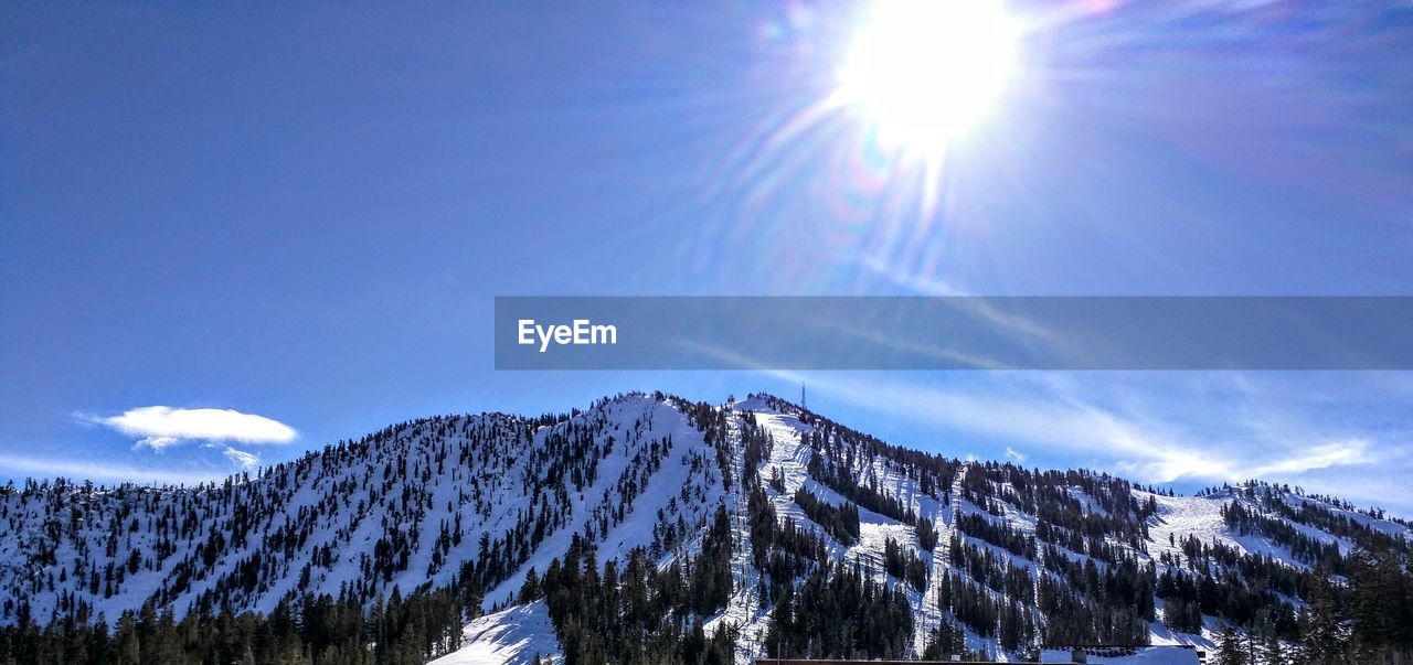 Scenic view of snowcapped mountains against blue sky on sunny day