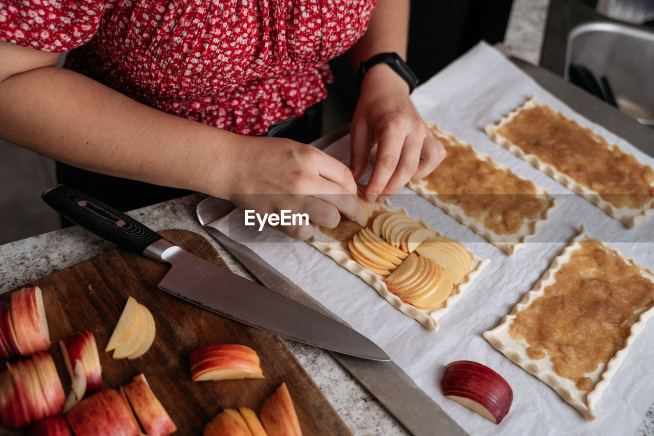 Midsection of young adult women making pastry with apples