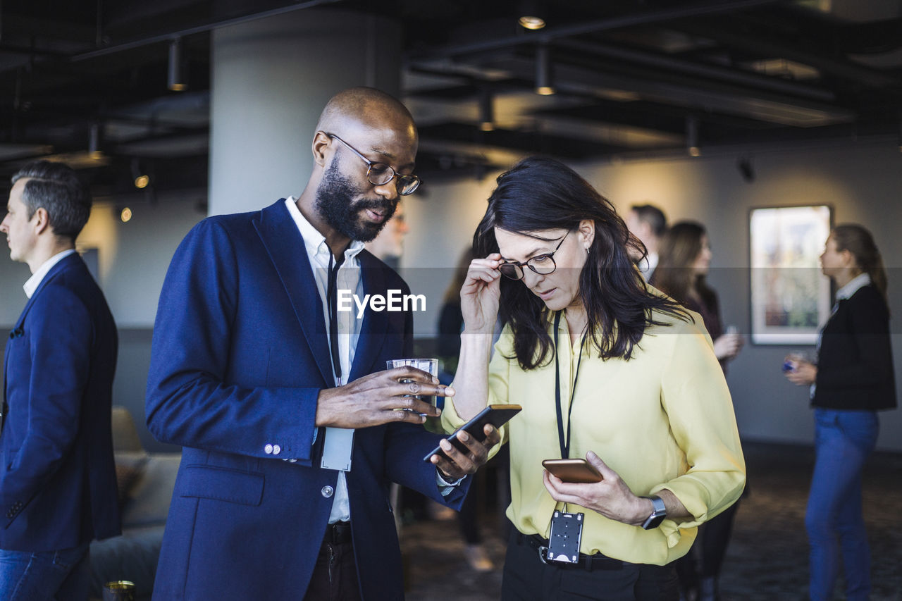 Male entrepreneur showing smart phone to female colleague in office