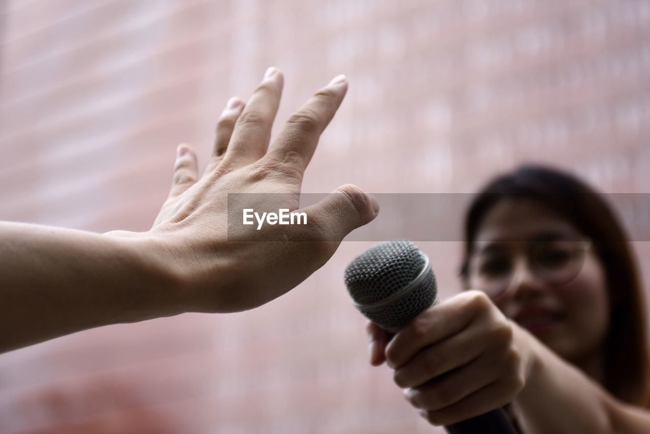 Cropped hand of person showing stop sign to female journalist