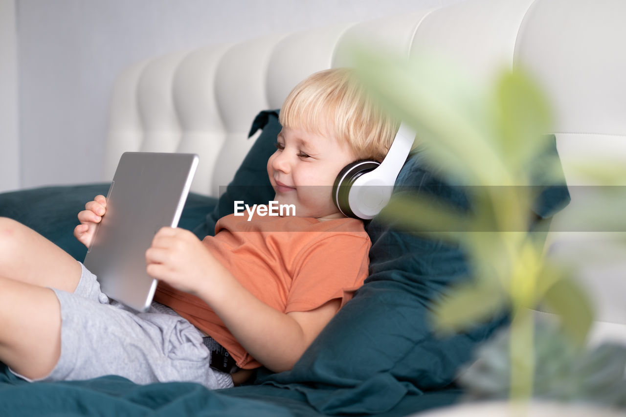 Cute boy using digital tablet on sofa