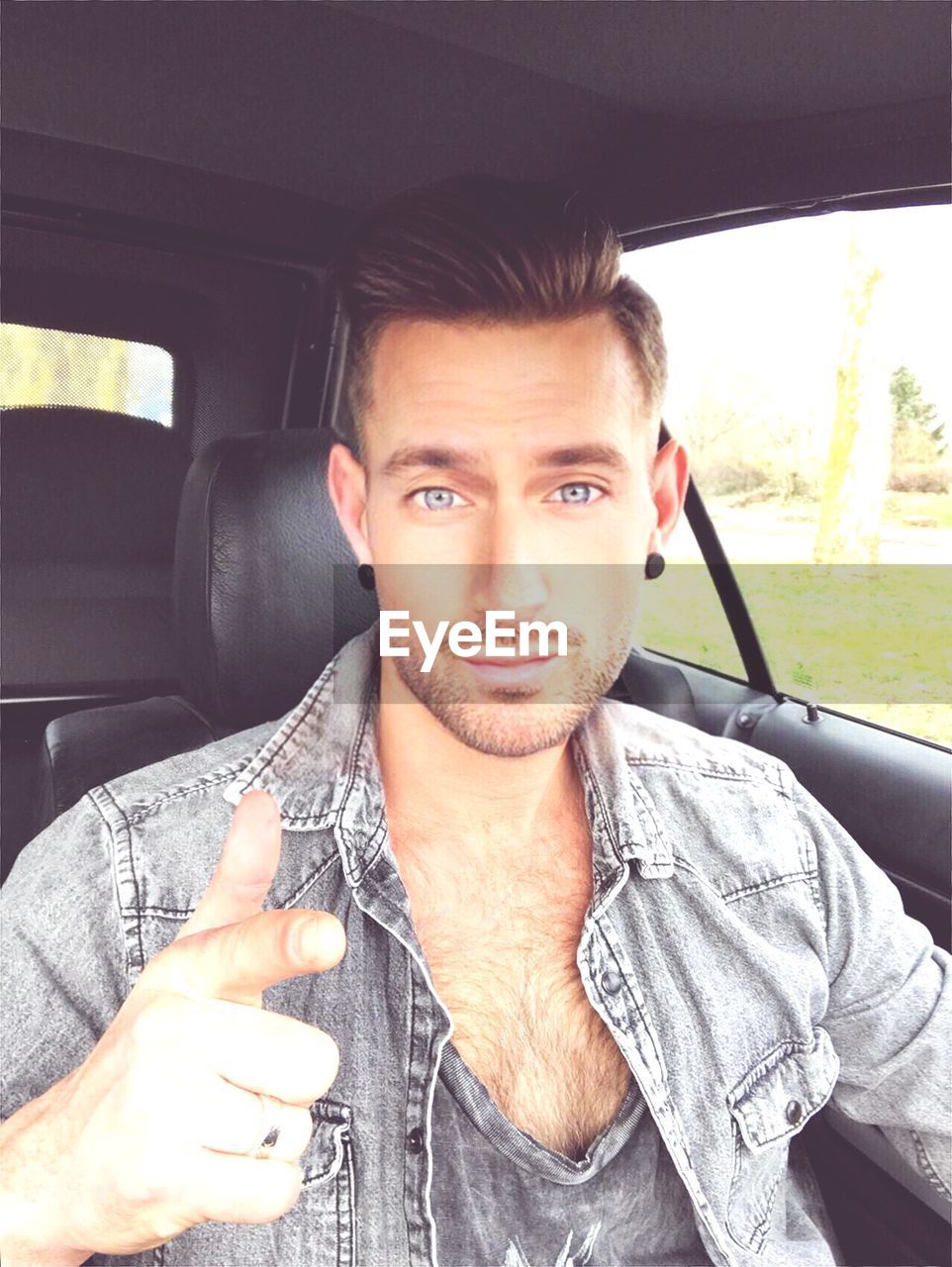 PORTRAIT OF YOUNG MAN WITH CAR IN BACKGROUND