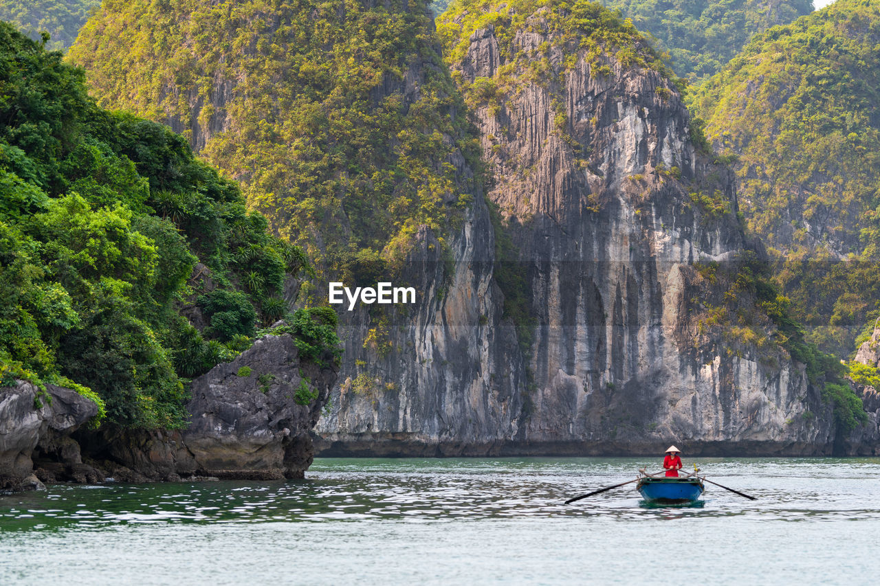 Man sailing in lake by rock formation