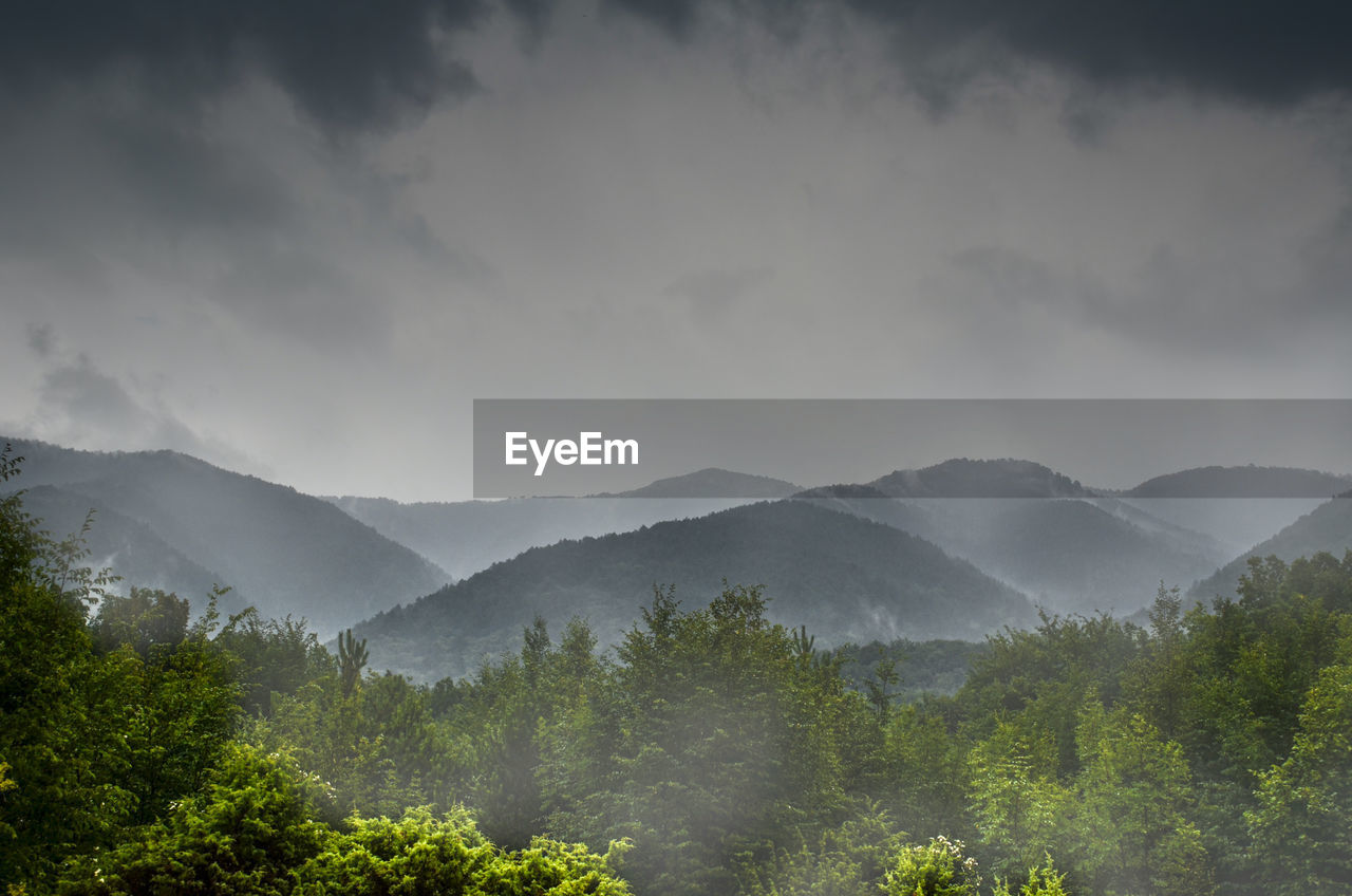 Scenic view of foggy mountains against sky