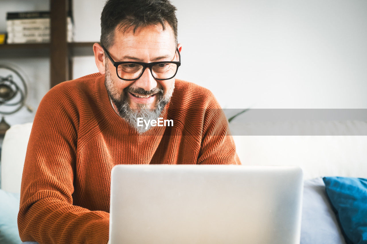 young man using laptop while sitting on sofa at home