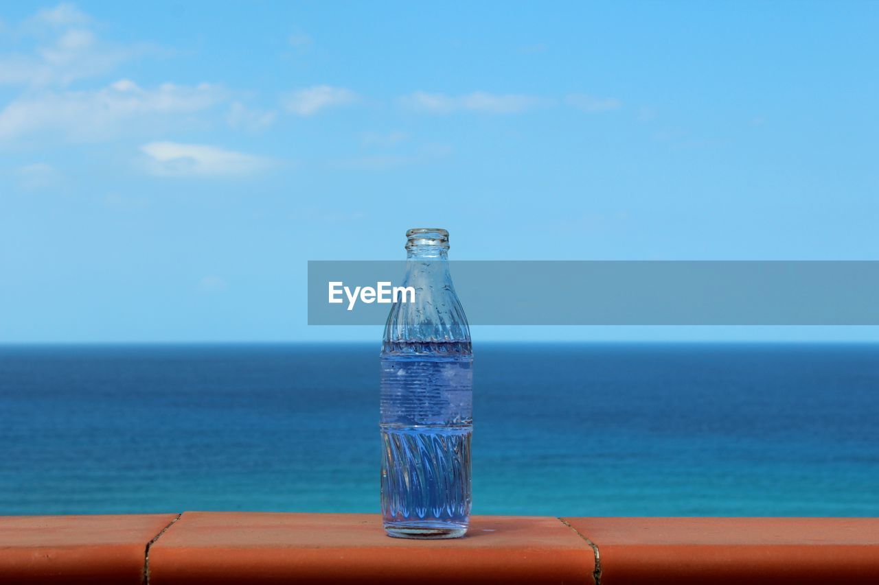 Water bottle on blue sea against sky