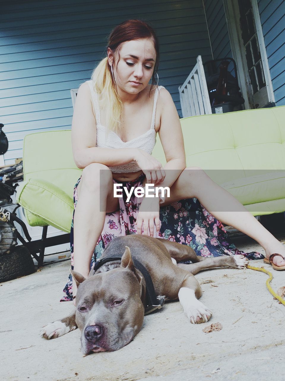 Low angle view of teenage girl looking at dog lying on floor while sitting outdoors