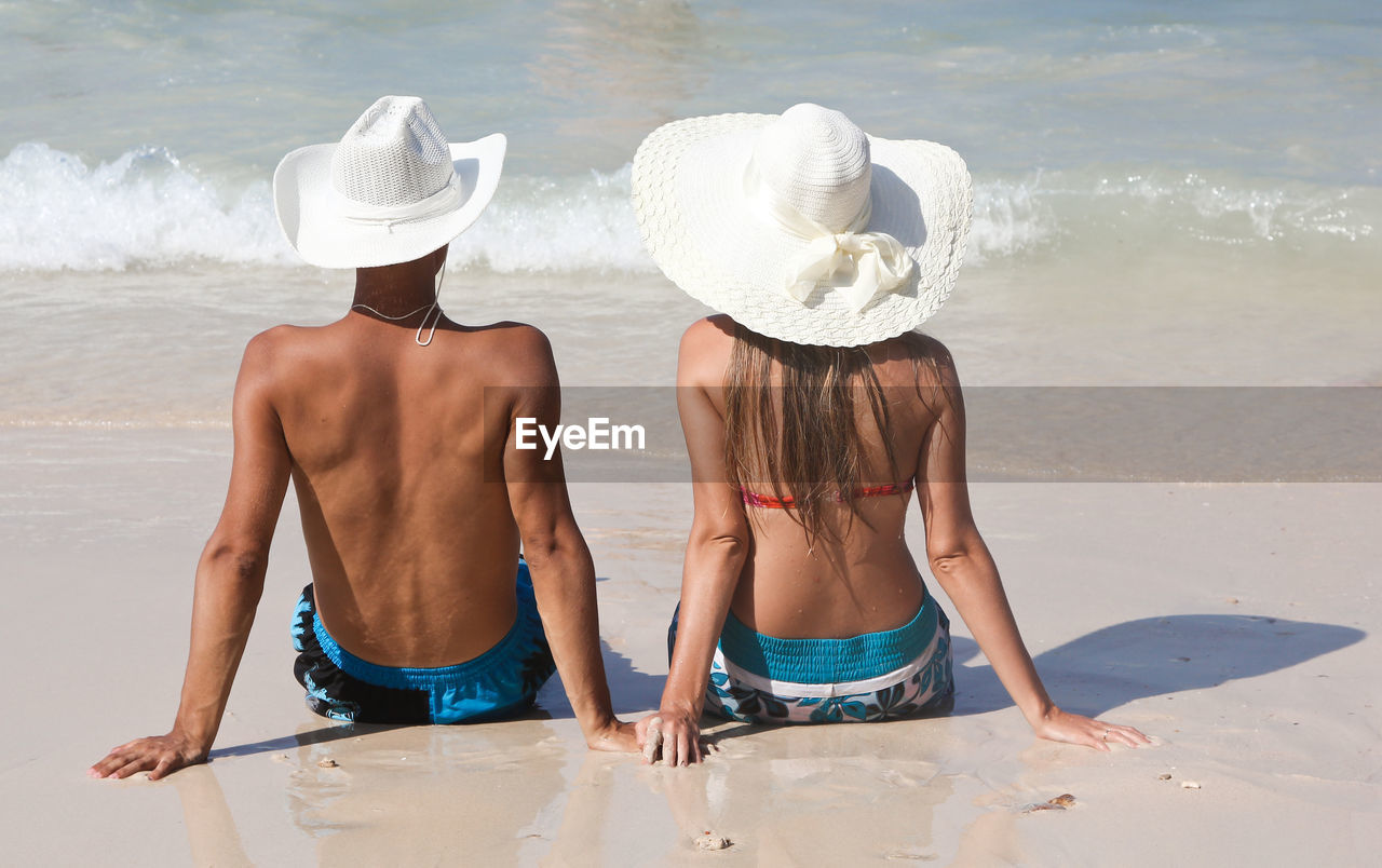 Rear view of couple sitting on beach