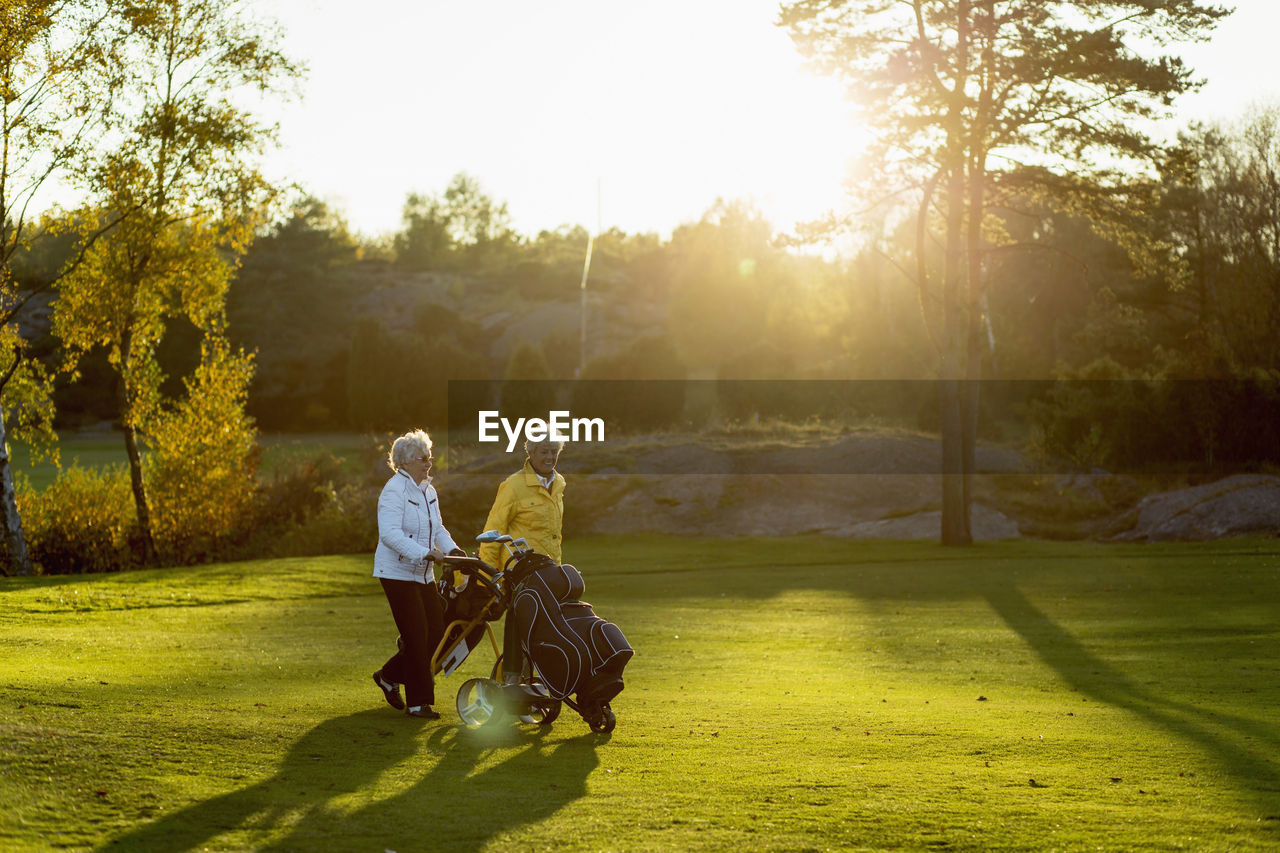 Senior women walking with golf bags on grassy area