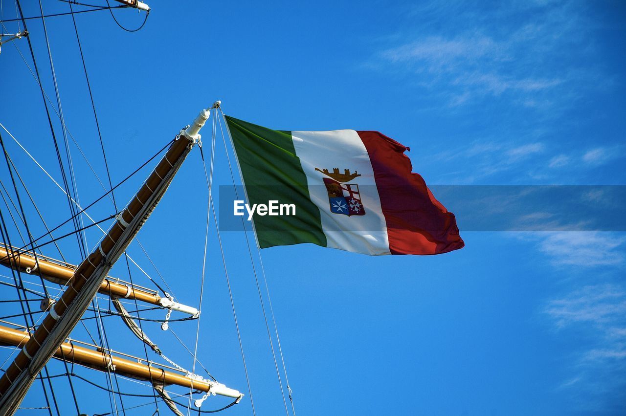 Low angle view of italian flag on tall ship against blue sky