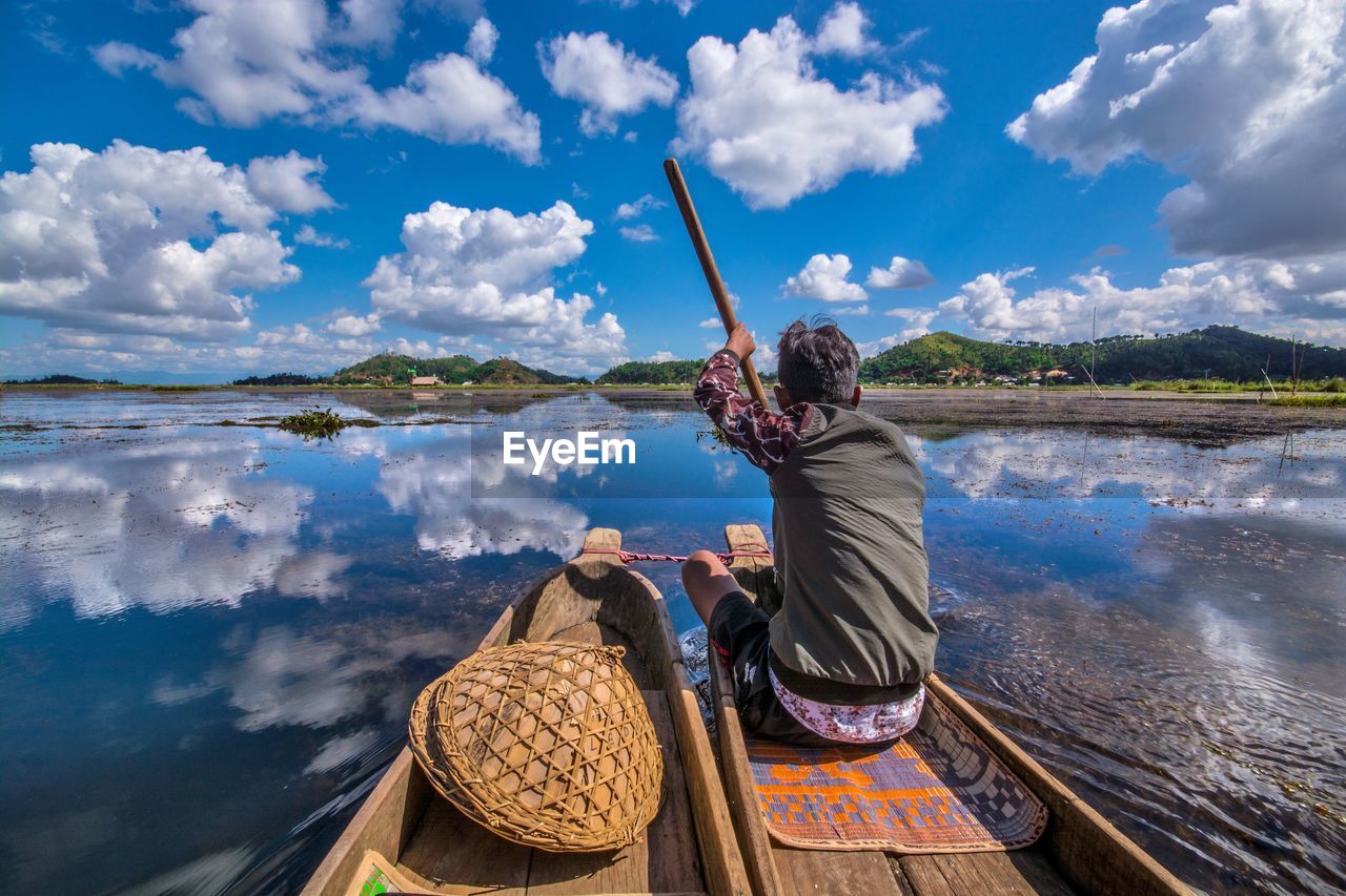 Rear view of woman sitting on mountain against sky