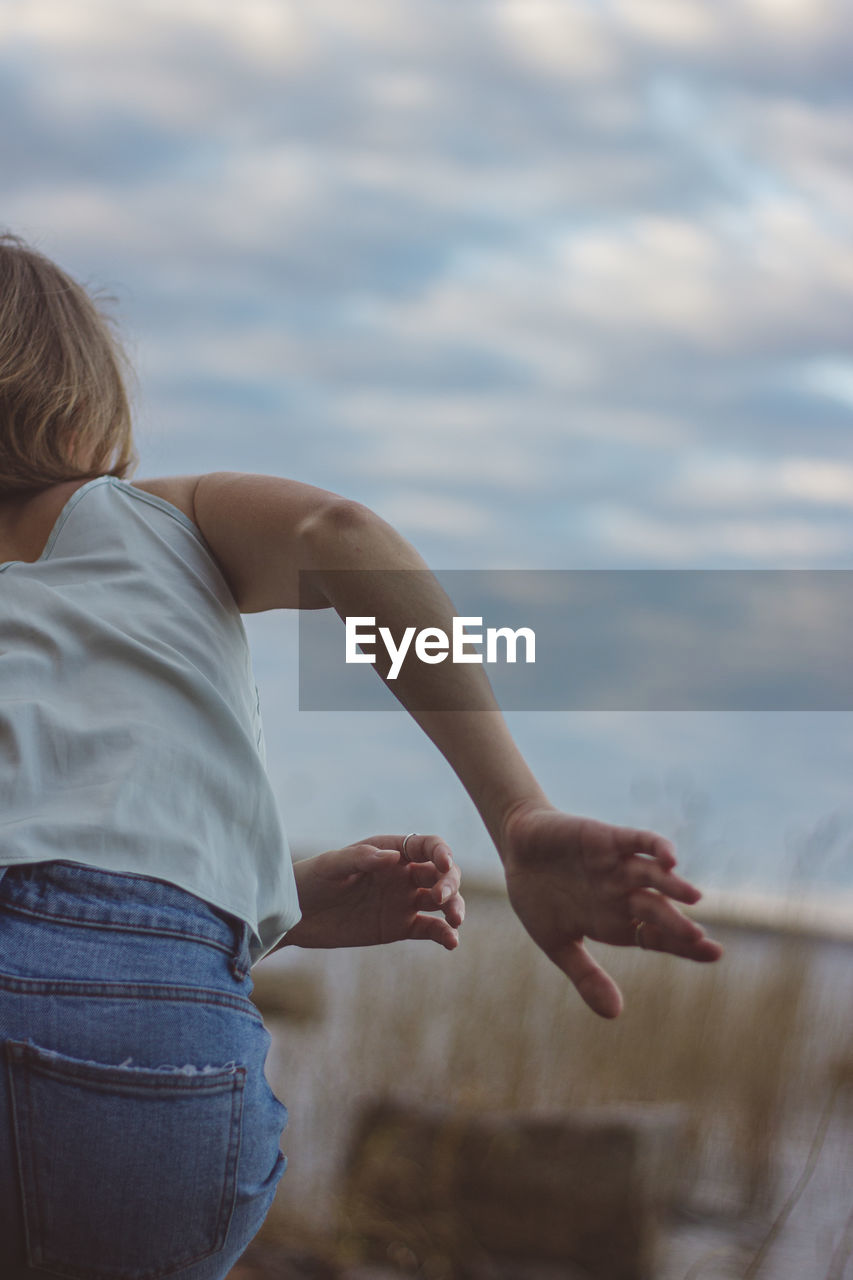 Rear view of woman dancing against sky
