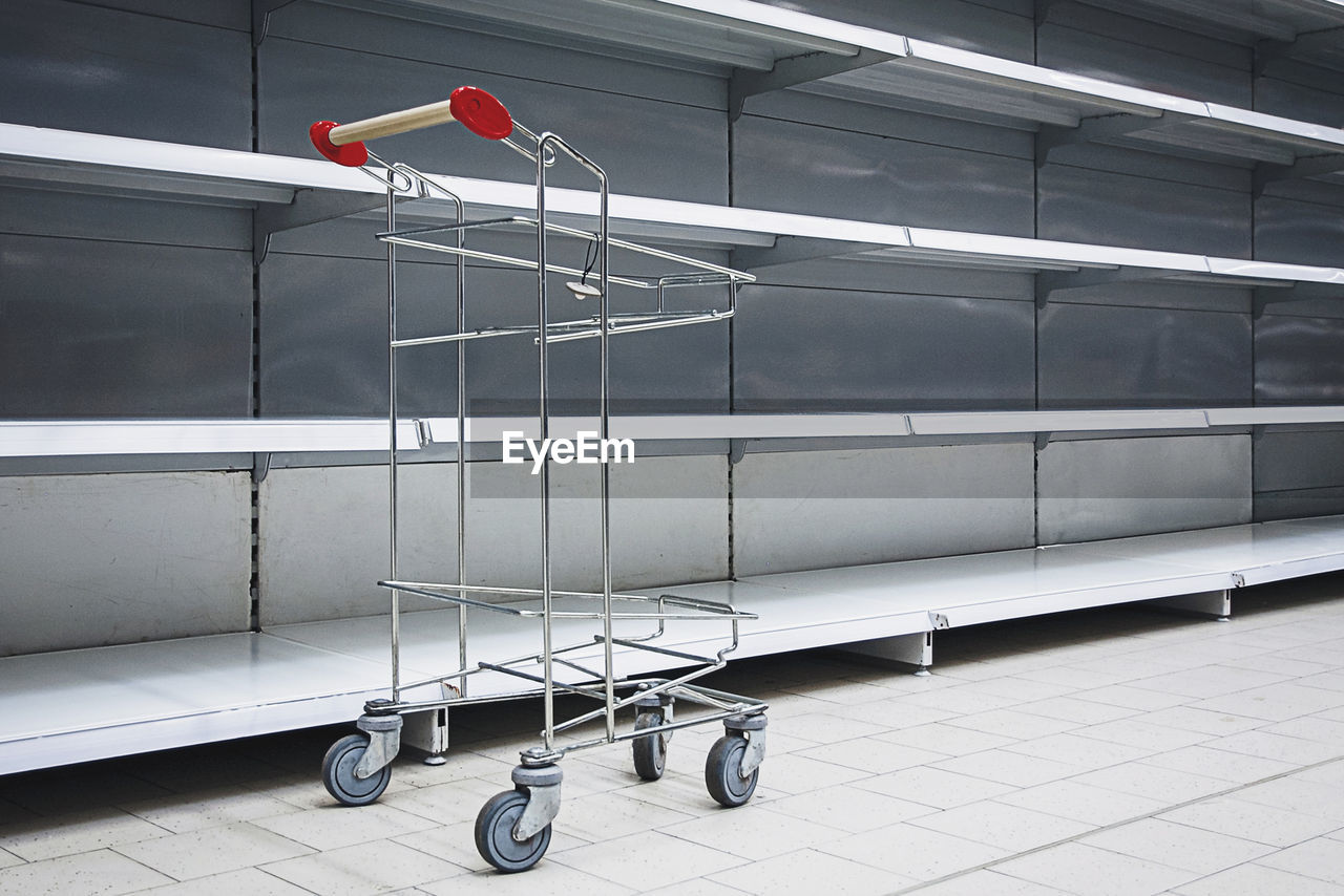 Empty shelves and shopping cart in supermarket, all sold out due to panic