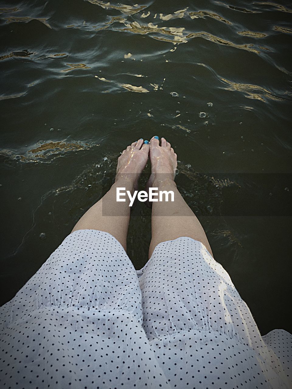 LOW SECTION OF WOMAN WITH LEGS IN WATER