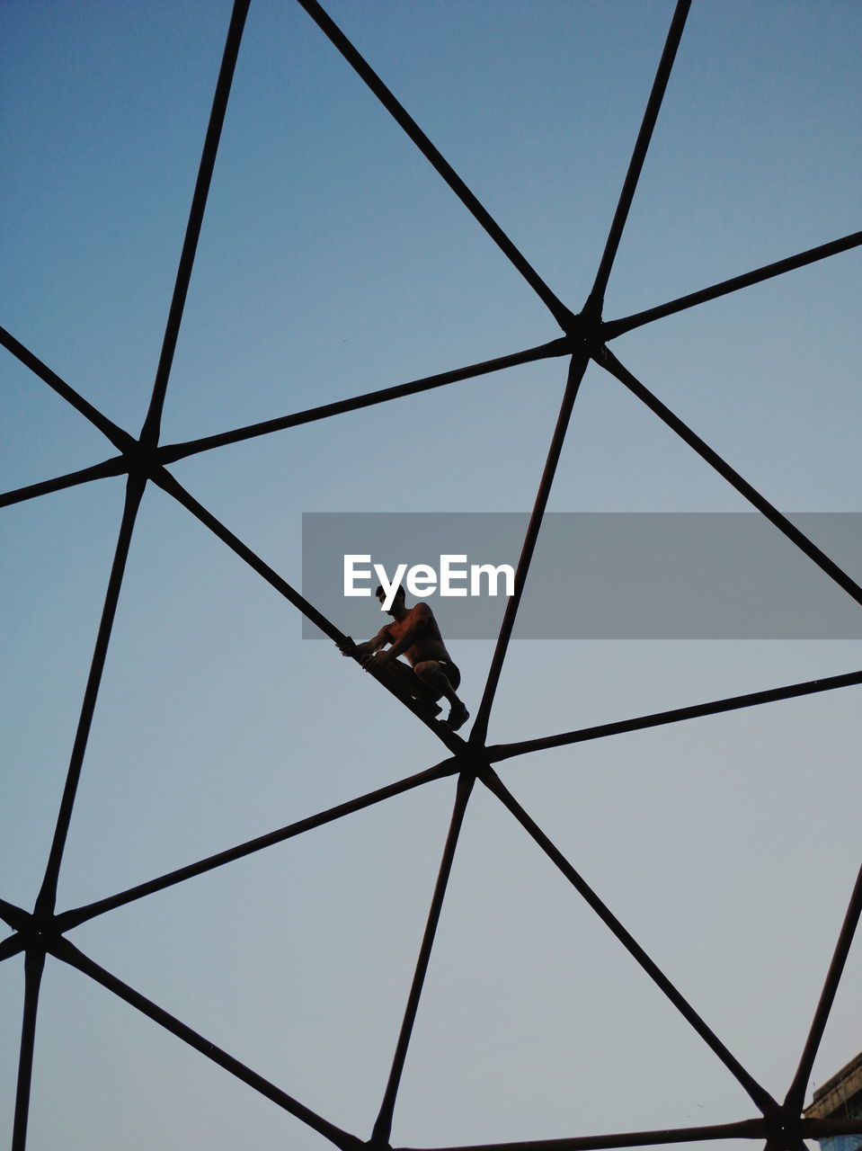 LOW ANGLE VIEW OF MAN CLIMBING AGAINST SKY