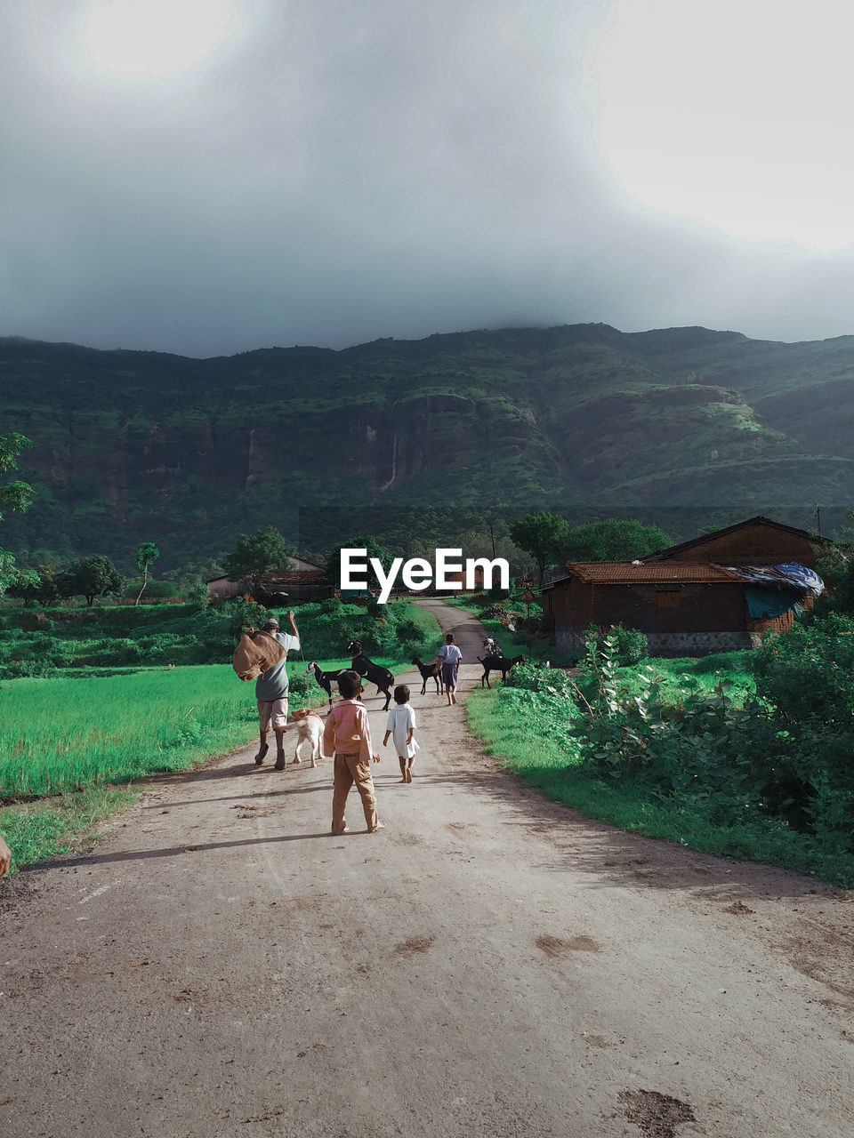 REAR VIEW OF PEOPLE WALKING ON BUILDING AGAINST MOUNTAIN