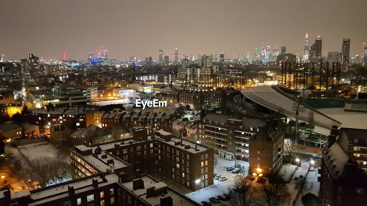 HIGH ANGLE VIEW OF ILLUMINATED CITYSCAPE AGAINST SKY DURING WINTER