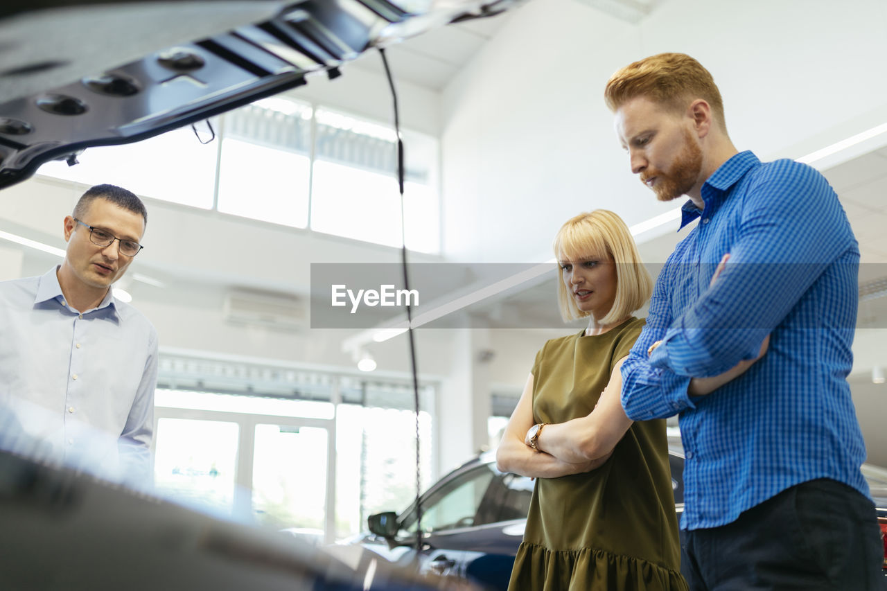 Salesman advising customers in car dealership