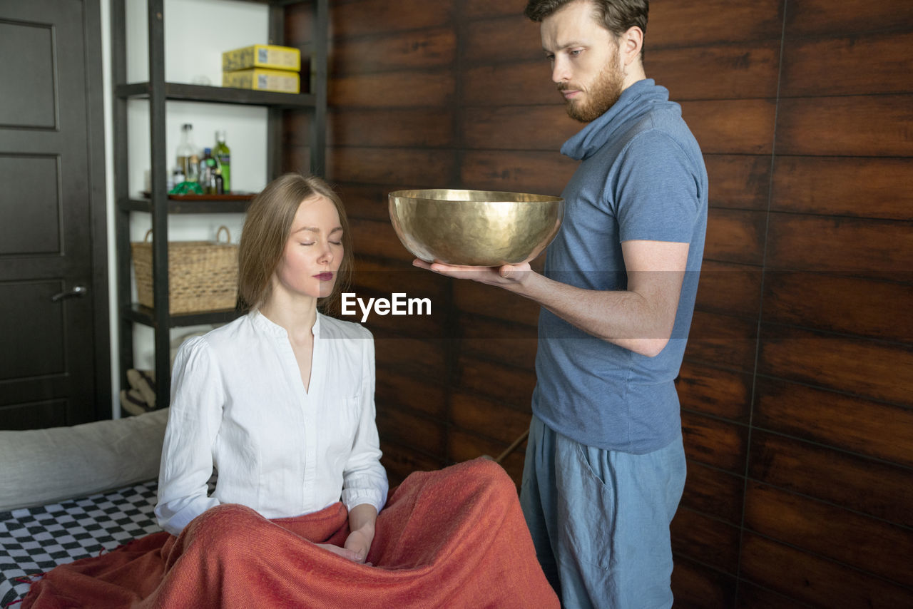 Beautiful woman meditating with singing bowl