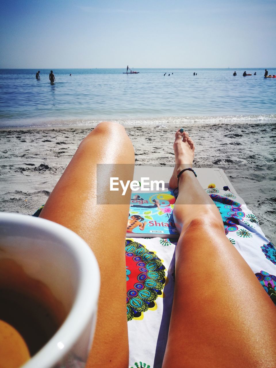 LOW SECTION OF WOMAN ON BEACH AGAINST SKY