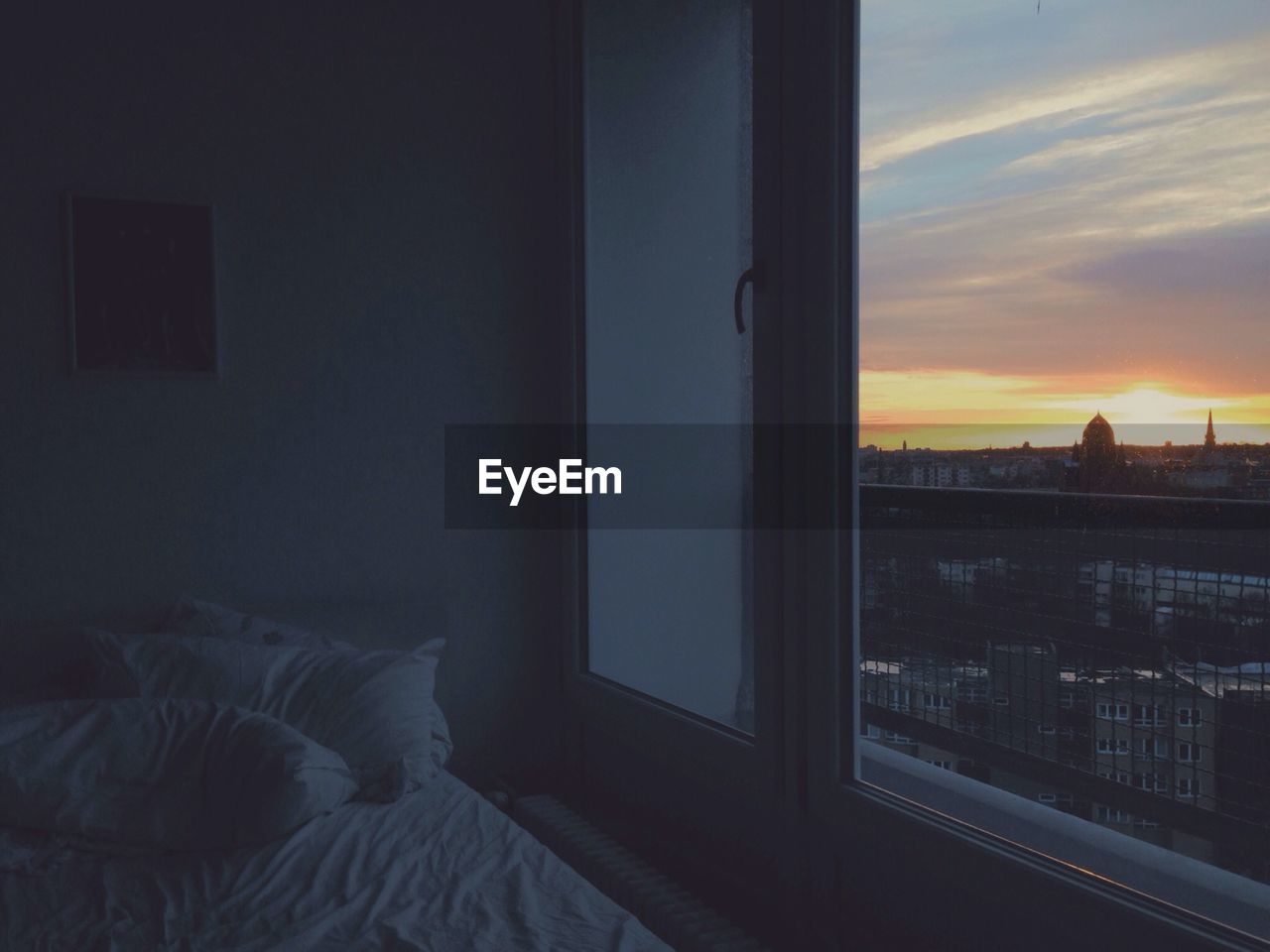 View of cityscape at sunset through bedroom window