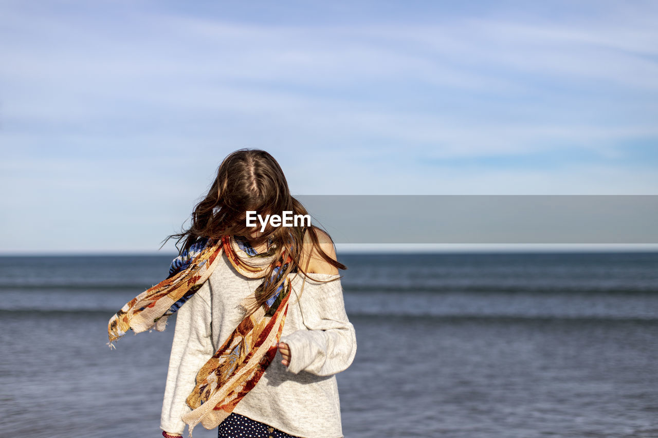 Woman wearing scarf standing against sea