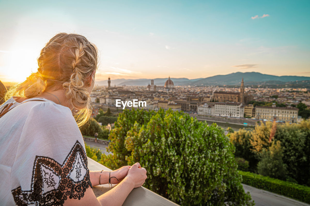 REAR VIEW OF WOMAN LOOKING AT CITY