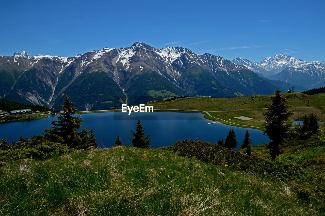 Scenic view of lake and mountains against blue sky