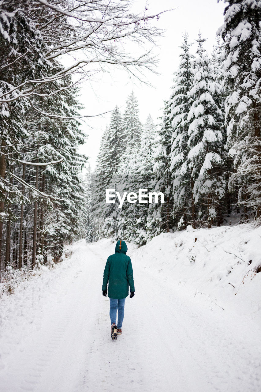 Rear view of woman walking on snow covered land