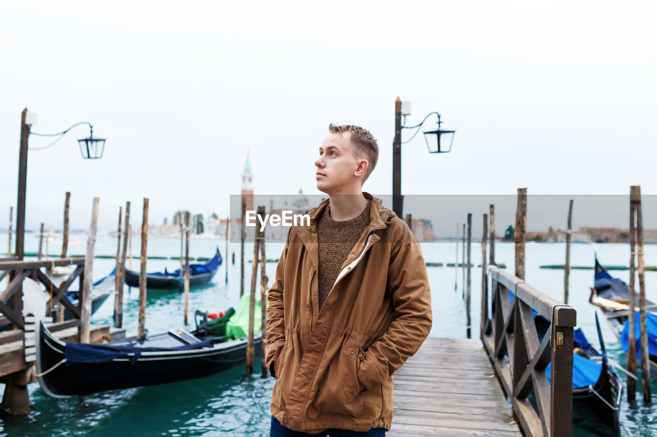 Young blond guy in a brown jacket in middle of streets of venice