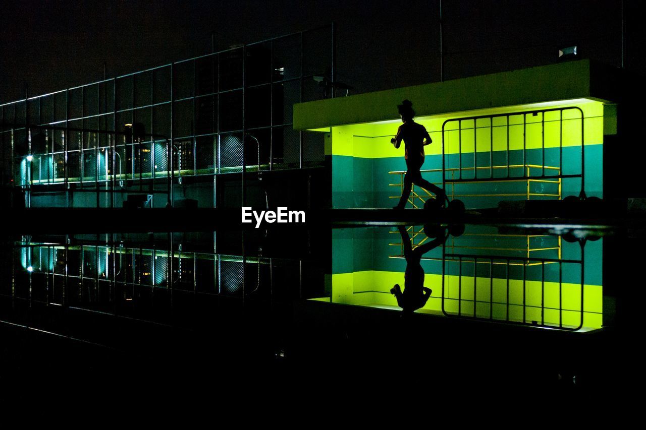 Full length of silhouette woman jogging in city at night