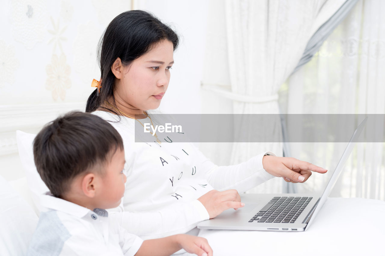 Mom is teaching children using a notebook for learning.