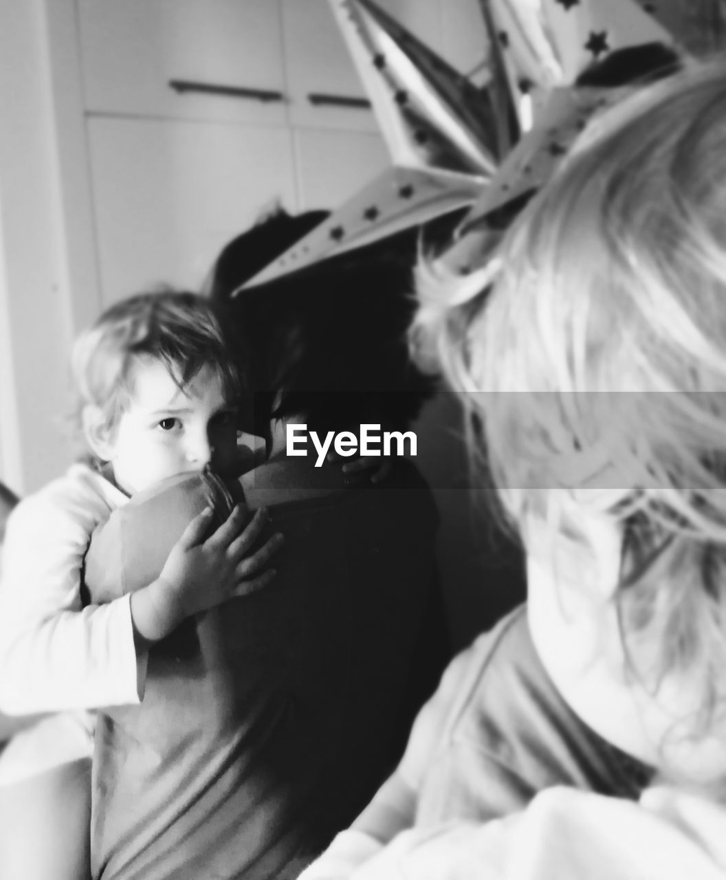 Mother carrying son against mirror with reflection at home